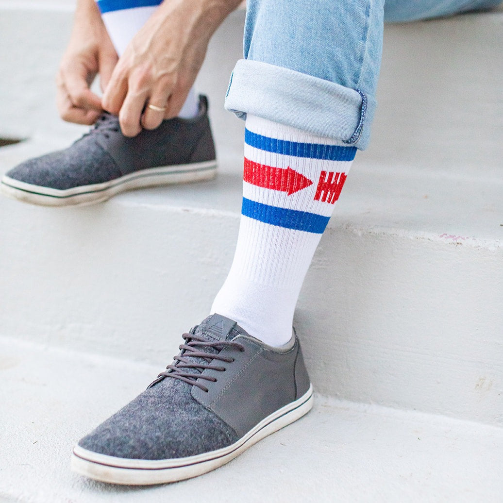 a man sitting on a step tying his shoes and wearing a pair of white socks with red, white, and blue stripes